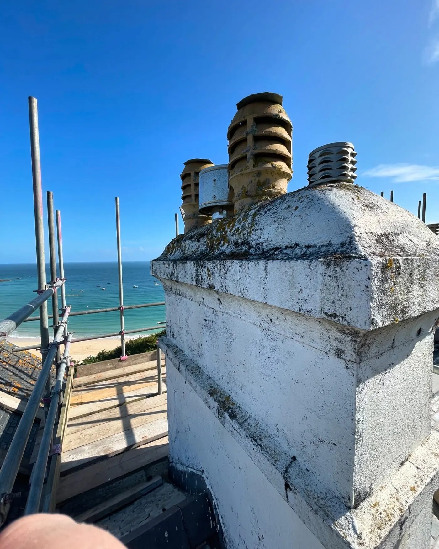 Chimney repainted high on a scaffold overlooking the sea