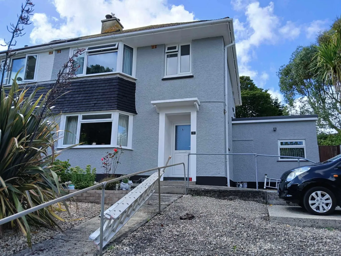 Grey-painted rendered semi-detached house with white trims