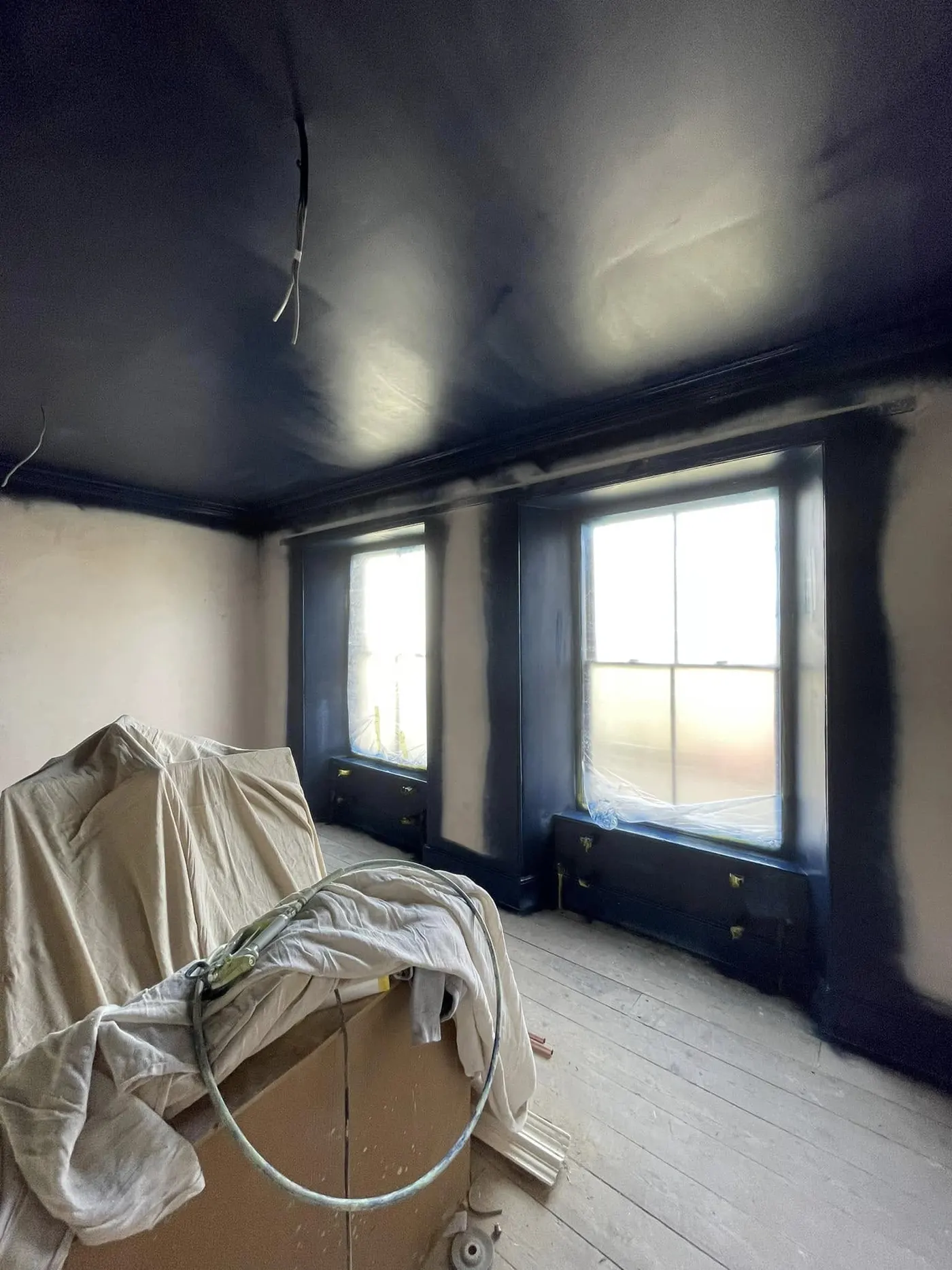 Navy ceiling being painted in a sheeted room