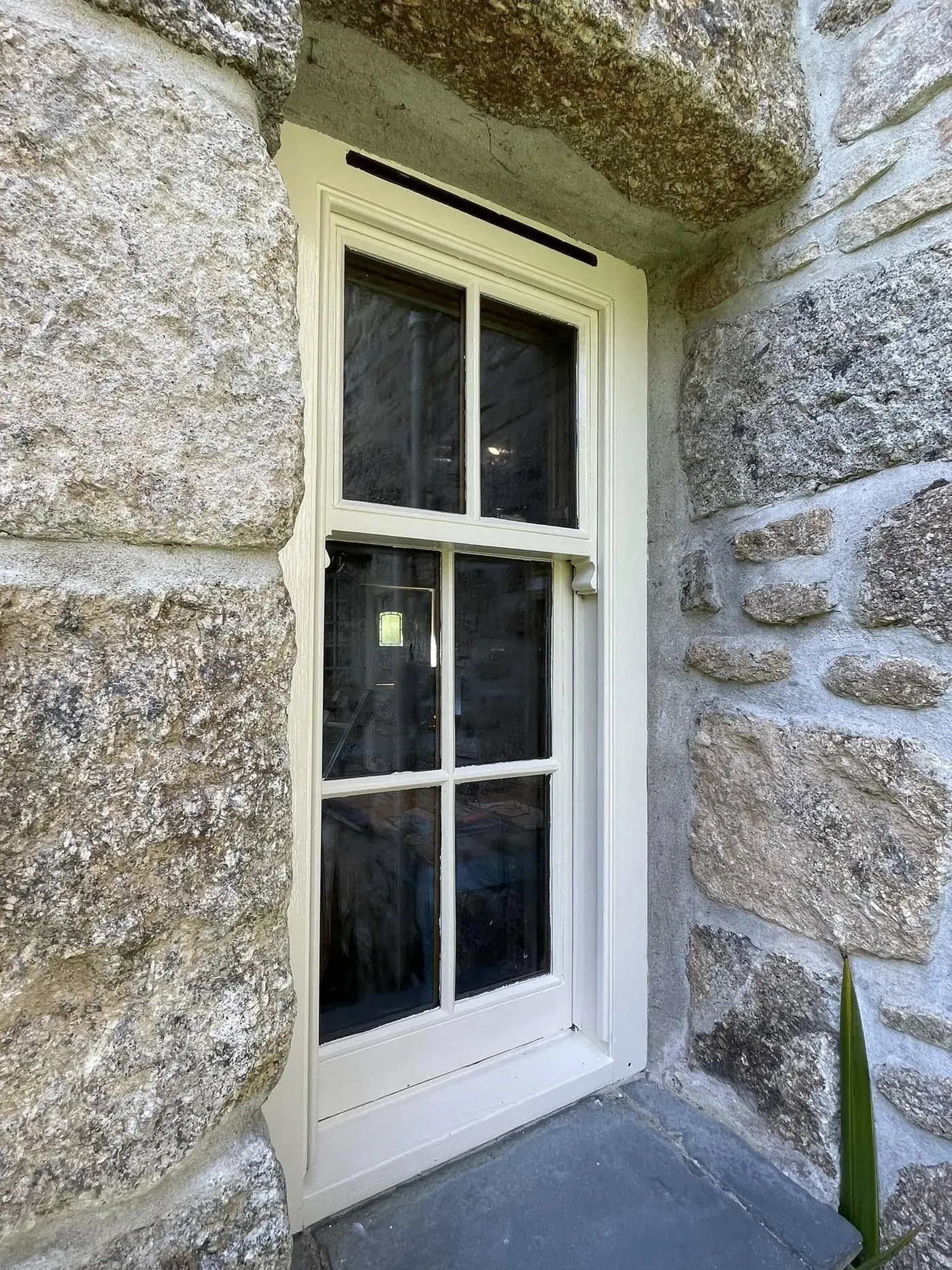 Sash window being restored in a granite opening