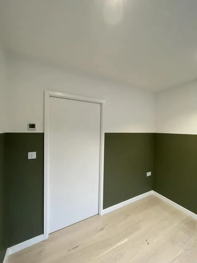 Two-tone room with deep green lower walls and white door
