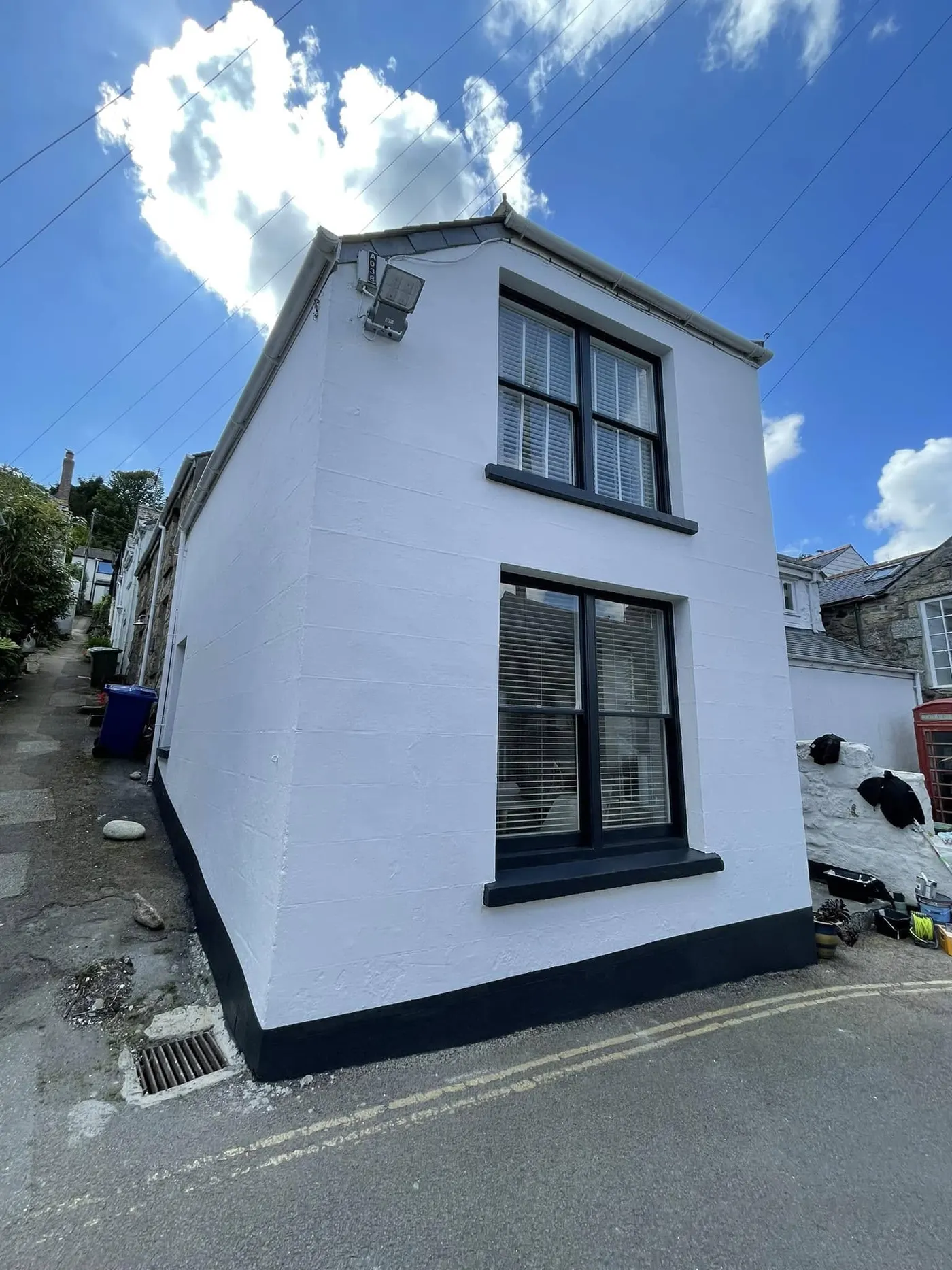 White-rendered cottage with dark window frames and plinth